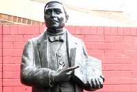 2 metre tall bronze statue of former President of Mexico, Benito Juarez, against a red painted brick wall