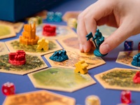 Close up of a person moving a piece while playing a colourful boarad game