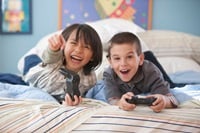 Two children hold video game controllers as they play a game.