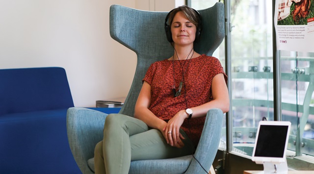Person sitting on a chair and listening to headphones.